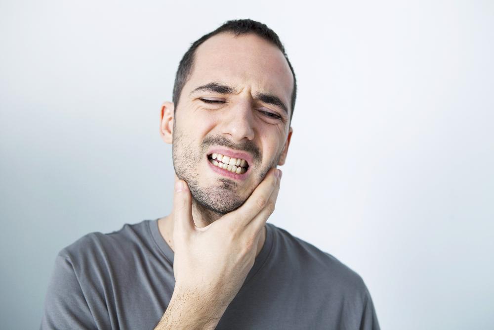 Man holding his jaw due to dental pains