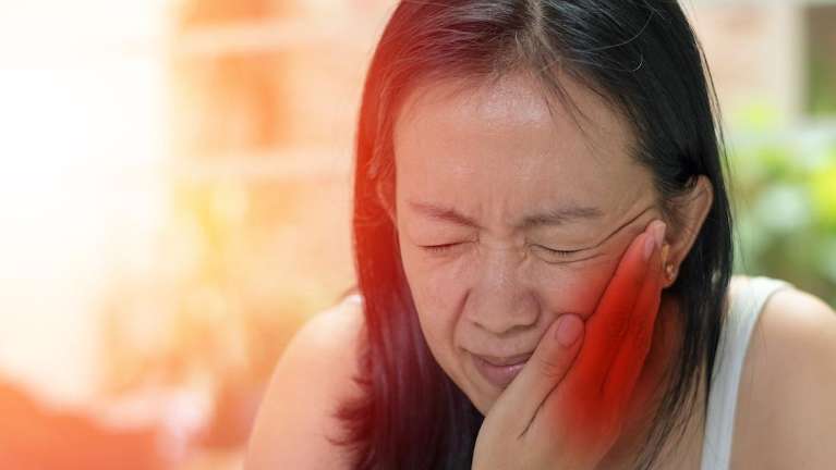 A patient holding her jaw due to toothache at Pradera Dental in Sterling,CO.
