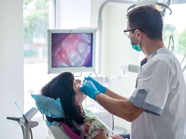 Dentist examining patient's teeth using Intraoral cameras at Pradera Dental